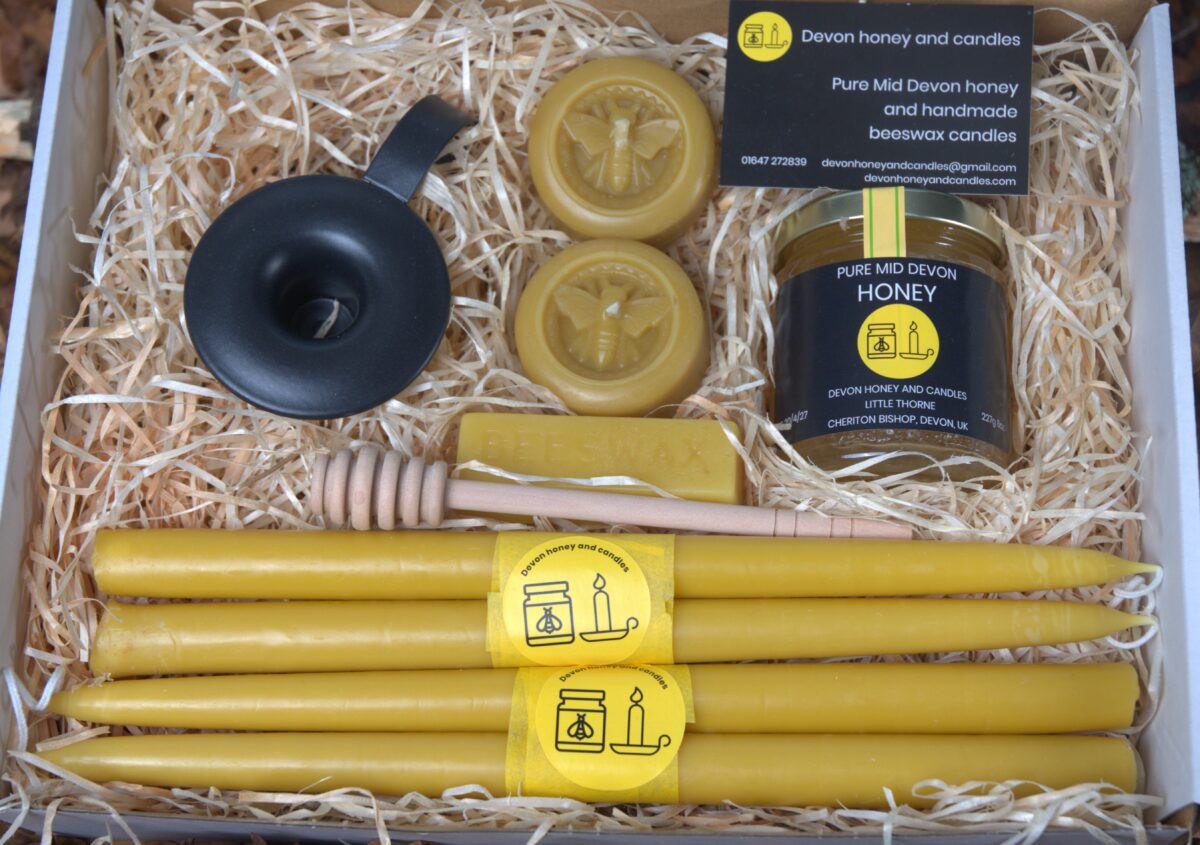 4 hand dipped beeswax candles, one candle holder, 2 round beeswax candles , one block of beeswax, a jar of Pure Mid Devon honey and a wooden dipper